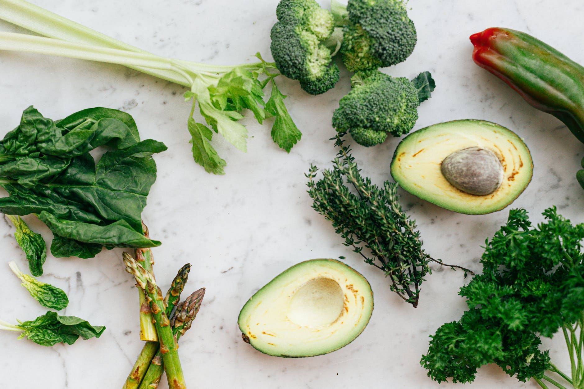 sliced avocado fruit and green vegetable on white chopping board