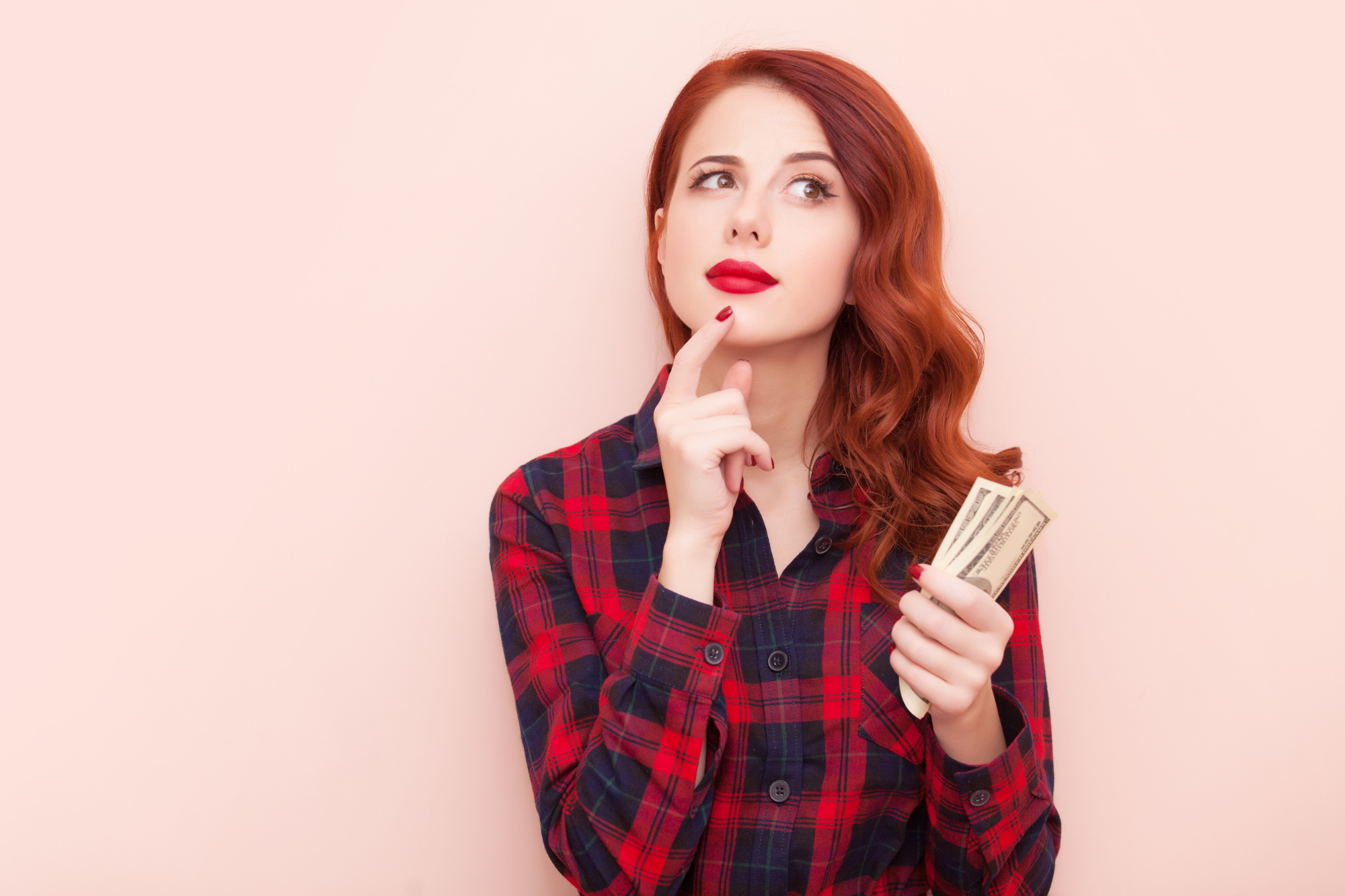 low carb on a budget girl with red hair thinking and holding money